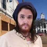 Young man with long dark hair and scruffy beard